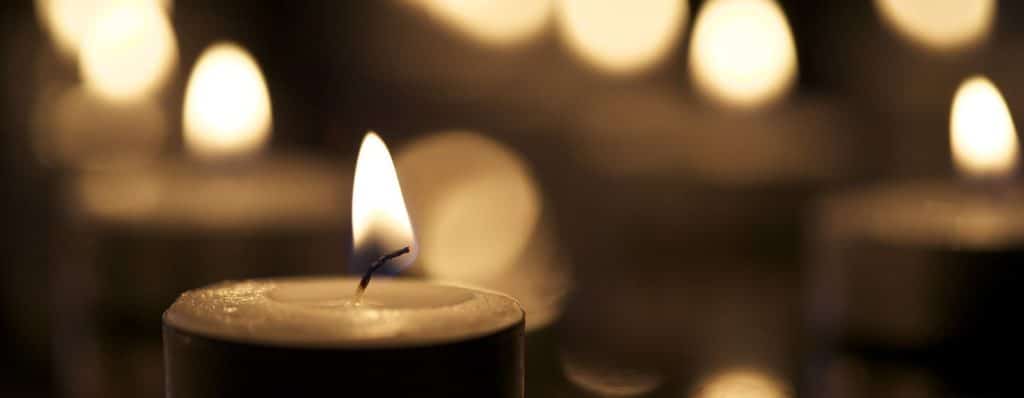 Single tea candle against a blurred background of multiple candles.
