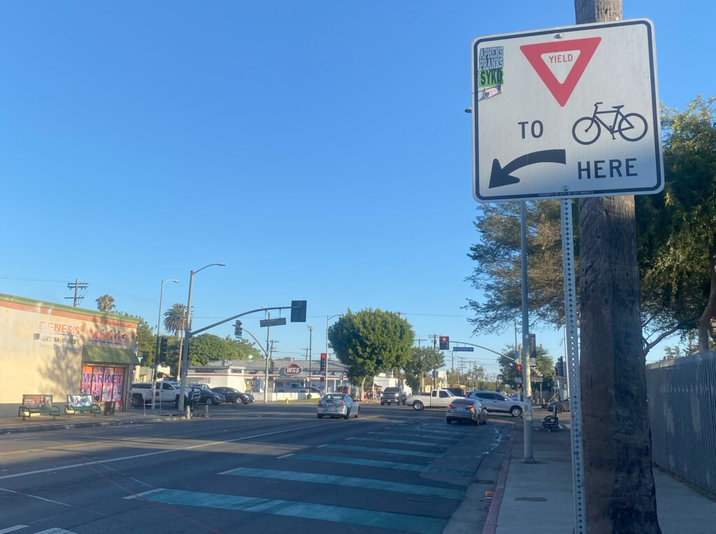 Yield to Bicyclist Sign above green dashes on street where bike lanes intersection At Avalon Boulevard and Manchester Avenue in L.A.
