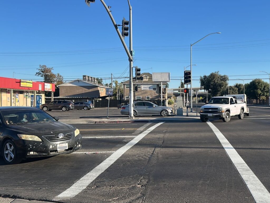 Vehicles entering the crosswalk at the intersection of First Street and Olive Street.