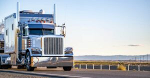 Semi-truck driving along farmland.