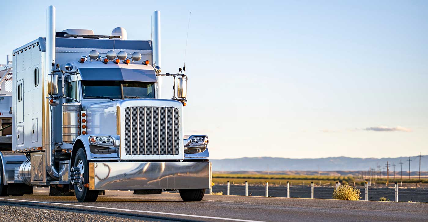 Semi-truck driving along farmland.