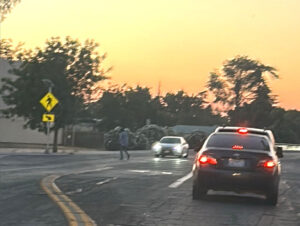 Pedestrian in crosswalk in low light in front of cars along Yosemite.
