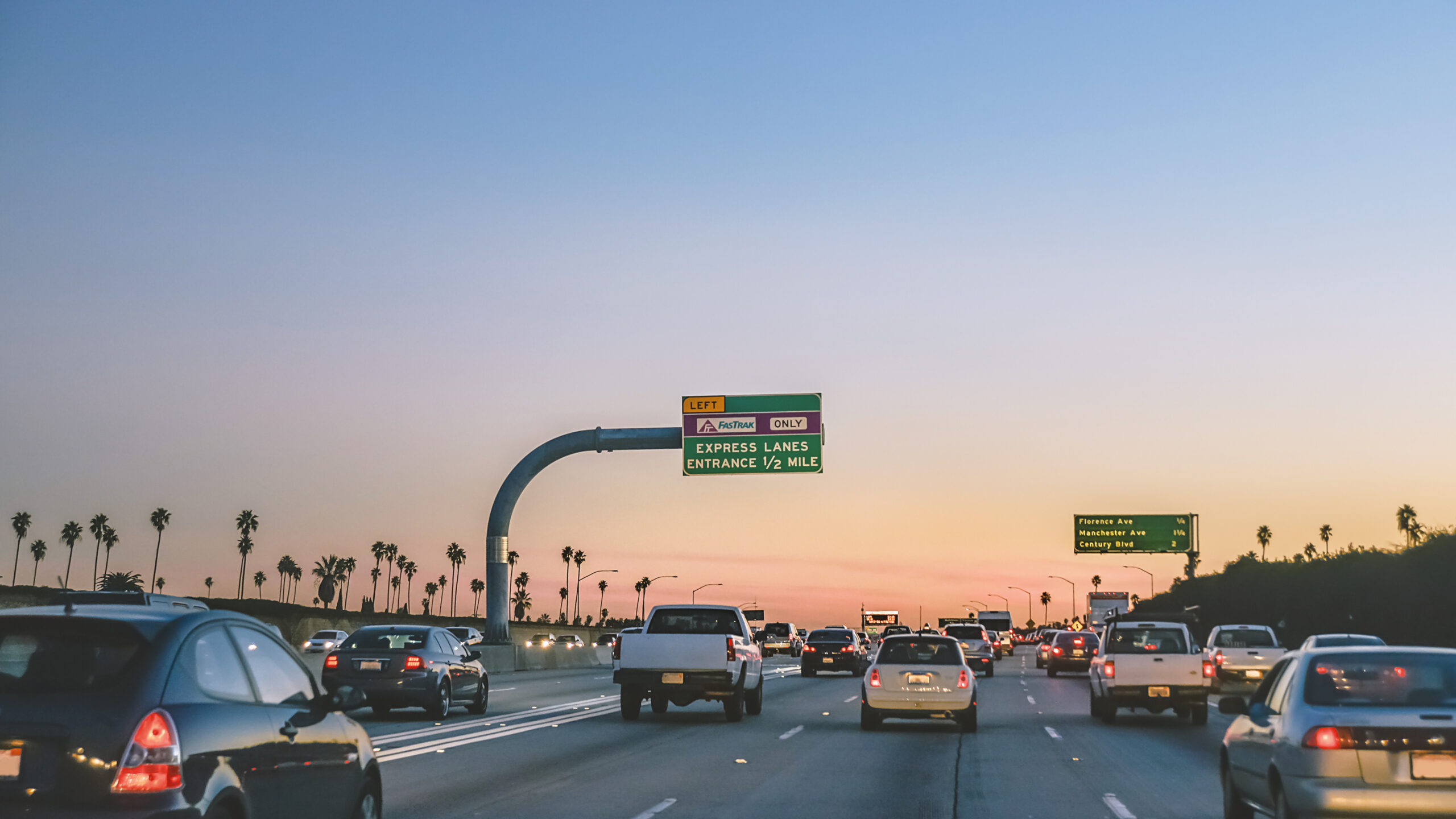 Express lane sign over busy freeway in Los Angeles at dusk